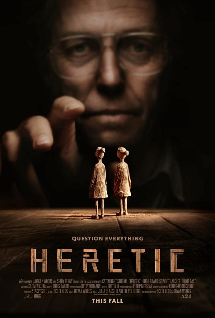 A large, blurry face ominously looms over two small wooden figurines on a table. The words "QUESTION EVERYTHING" and "HERETIC" are prominently displayed, evoking a mysterious suspense in the style of Color Out Of Space.