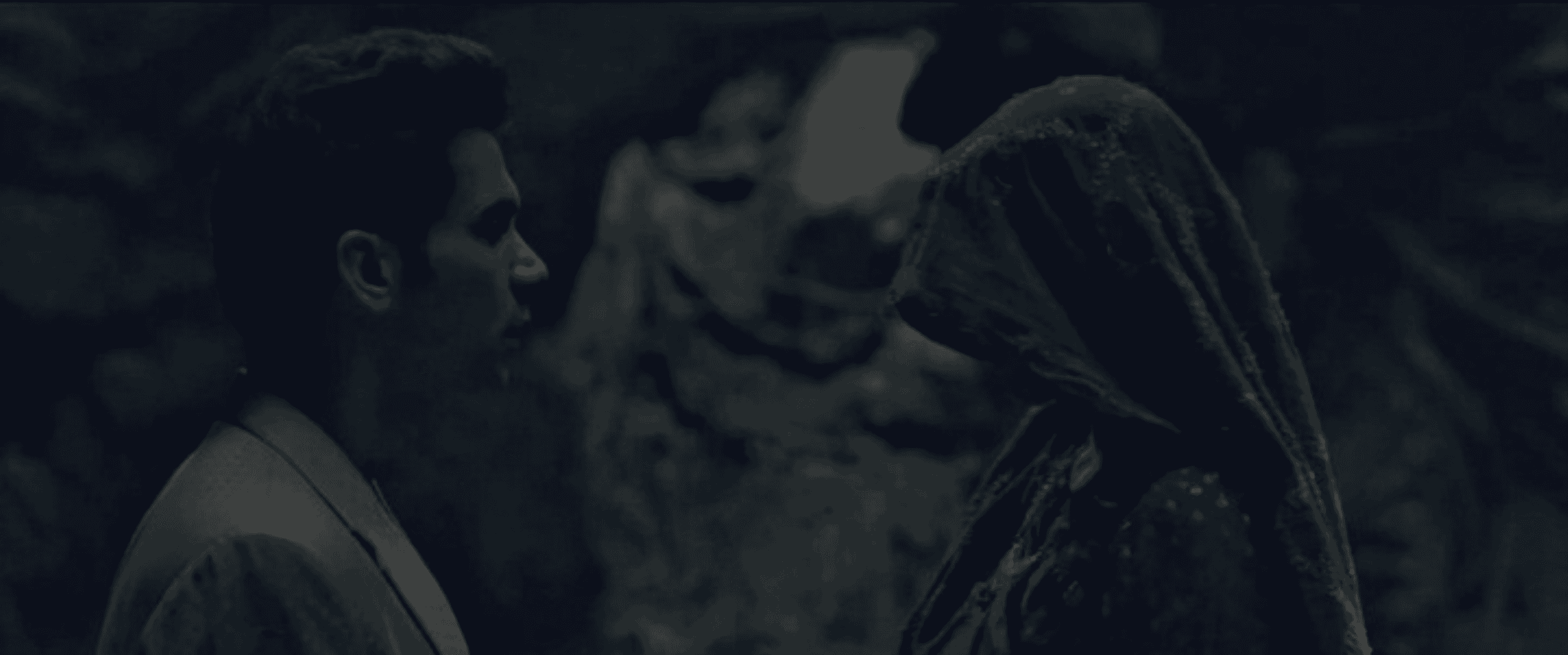 A man faces a woman whose face is covered with a red veil, standing together in a dimly lit, shadowy setting reminiscent of the haunting atmosphere found in A Nightmare on Elm Street: The Dream Master.