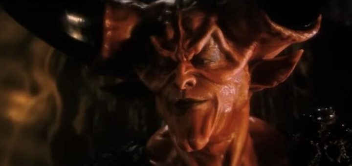 A close-up of a red-skinned, horned demon with sharp facial features and a sinister expression, wearing dark armor, in a dimly lit setting.