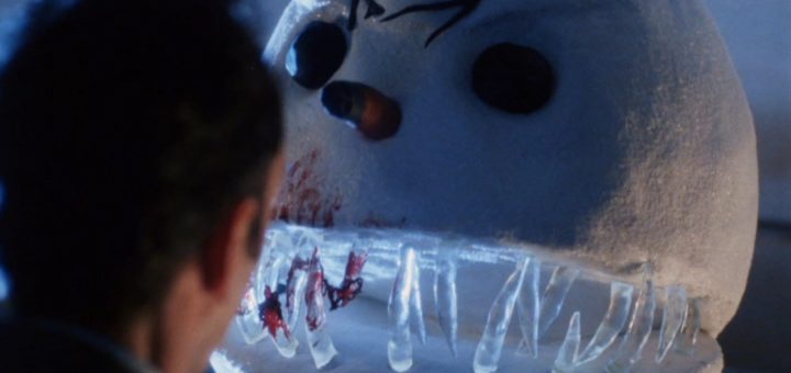 A man faces a large, menacing snowman with sharp icy teeth, dark eyes, and scars, resembling Jack Frost gone rogue. The snowman seems threatening yet absurdly fitting for a horror comedy set against a dark and eerie Christmas backdrop.