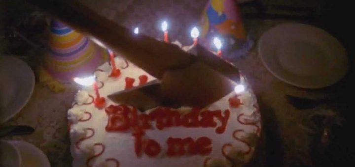 A decorated birthday cake with lit candles and the words "Birthday to me" is being cut in half by a large axe. Party hats and plates surround the cake, adding to the quirky Birthday Celebration scene.