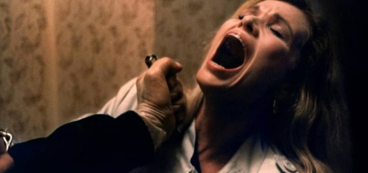 A woman with blonde hair screams in fear, her mouth wide open, as a hand holding a knife approaches her throat in a dimly lit, tense scene reminiscent of the terror in New York Ripper.