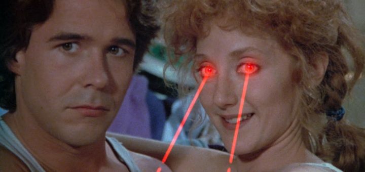 A man and woman sit close together. Channeling a sci-fi horror vibe inspired by H.P. Lovecraft’s Color Out Of Space, the woman smiles as bright red laser beams shoot from her eyes, while the man looks ahead with a neutral expression.